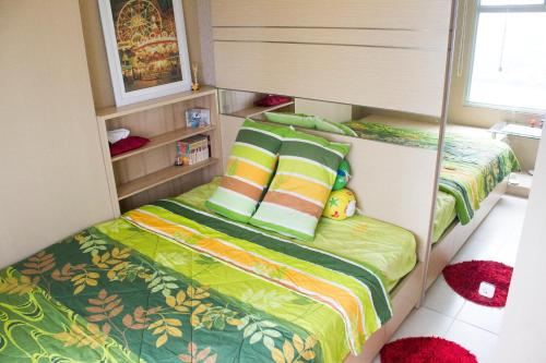 a small bedroom with a bed with green sheets and pillows at Green Bay Pluit Apartment - Indra in Jakarta