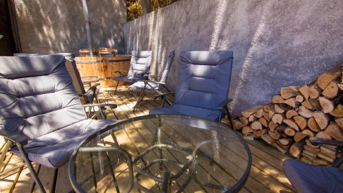 two chairs and a glass table next to a pile of fire wood at Comarca Lodge in Pichilemu
