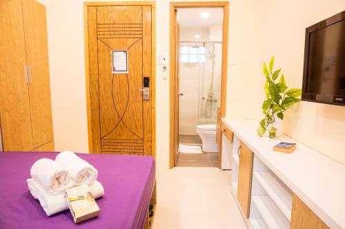 La salle de bains est pourvue d'un lit violet, d'une télévision et de toilettes. dans l'établissement Jen & Friends House, à Hô-Chi-Minh-Ville