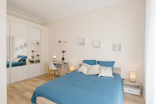 a white bedroom with a blue bed and a desk at Flat Saint Charles in Marseille