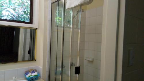 uma casa de banho com um chuveiro e uma porta de vidro em The Islands Inn Motel em Airlie Beach