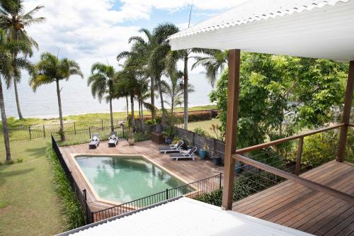 uma vista aérea de um quintal com uma piscina e um deque em ABSOLUTE BEACHFRONT BLISS - NEWELL BEACH - 10 Metres to the Ocean em Newell Beach