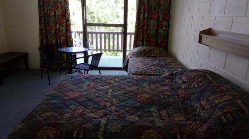 Schlafzimmer mit einem Bett, einem Tisch und einem Fenster in der Unterkunft The Islands Inn Motel in Airlie Beach