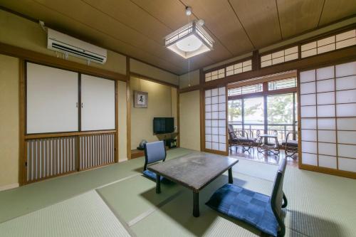 a living room with a table and chairs and windows at Asanokan in Ise