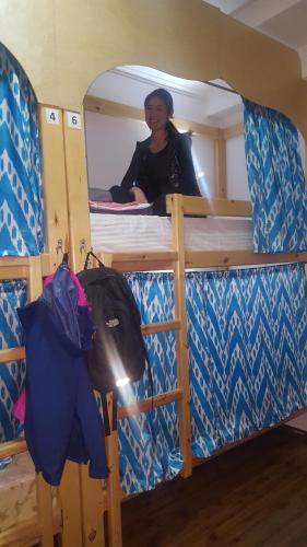 a woman sitting on a bunk bed in a bus at Amir Hostel in Samarkand