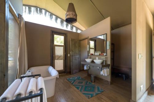 een badkamer met een bad, een wastafel en een spiegel bij Chundu Island in Victoria Falls
