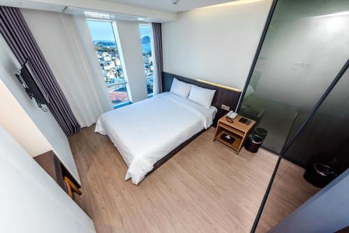 a small bedroom with a bed and a table at The First70 Hotel in Seogwipo