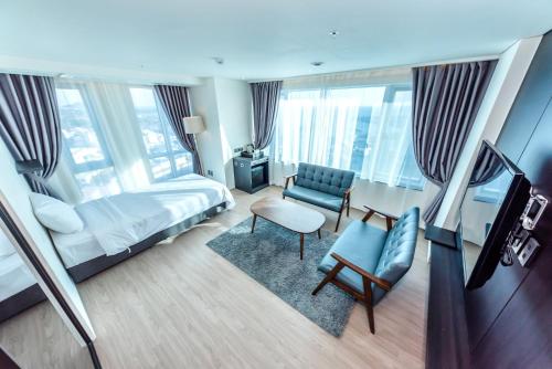 a hotel room with a bed and a chair at The First70 Hotel in Seogwipo