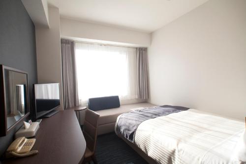 a hotel room with a bed and a television at Hotel Port Plaza Chiba in Chiba