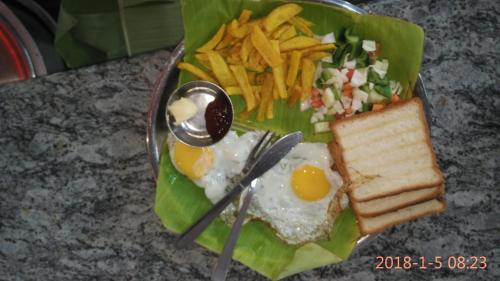 a plate of food with eggs and a salad and french fries at Hotel Varsha Hampi in Hampi