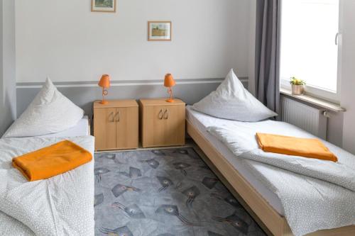 2 łóżka w pokoju z białą pościelą i pomarańczowymi poduszkami w obiekcie Apartment Widey Str. 54 w mieście Witten