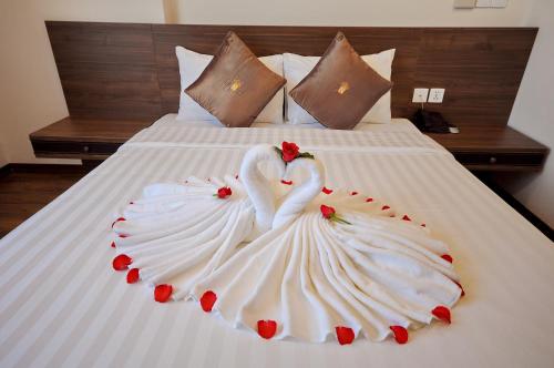 two swans dressed in white are sitting on a bed at Lenid Ocean View Hotel in Nha Trang