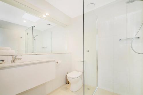 a white bathroom with a shower and a toilet at Kananda in Noosa Heads