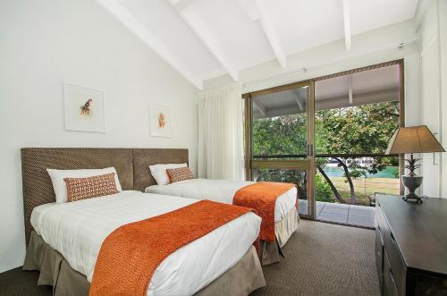 two beds in a room with a window at Kananda in Noosa Heads