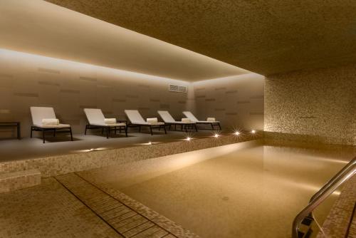 a room with a pool with white chairs and lights at Áurea Museum by Eurostars Hotel Company in Lisbon
