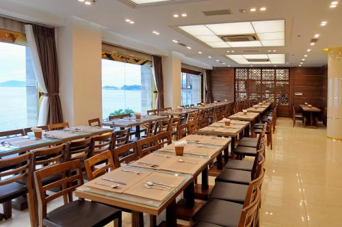 a long row of tables in a restaurant with windows at Lenid Ocean View Hotel in Nha Trang