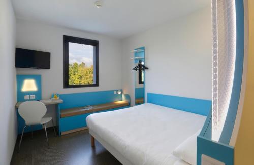 a bedroom with a bed and a desk and a window at First Inn Hotel Blois in Blois