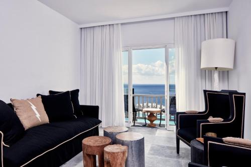 
a living room filled with furniture and a large window at Royal Myconian - Leading Hotels of the World in Elia Beach
