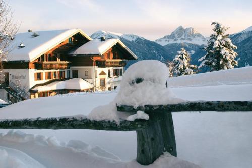 a snow covered fence with a house in the mountains at Herol - my mountain retreat in Luson