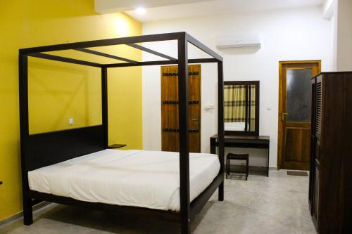 a bedroom with a black canopy bed and a desk at Villa Marina Hikkaduwa in Hikkaduwa