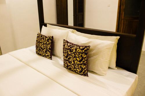 a white bed with three pillows on it at Villa Marina Hikkaduwa in Hikkaduwa