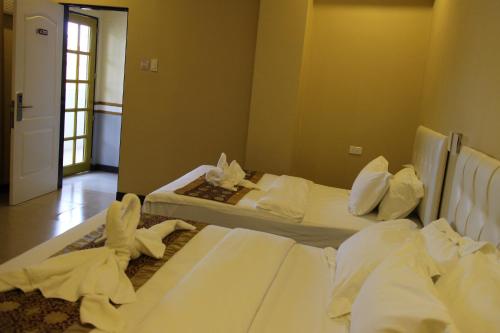 two beds in a hotel room with white sheets at Southview Hotel in Dumaguete