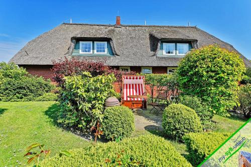 ein Haus mit einem roten Stuhl im Hof in der Unterkunft Landhaus Kroghooger Wai in Kampen