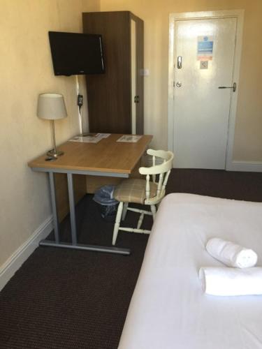 a desk in a hotel room with a bed and a desk with a computer at Gateway Lodge in Cleckheaton