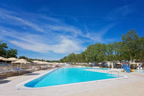 une grande piscine avec des chaises et des parasols dans l'établissement Easyatent Safari tent Bijela Uvala, à Poreč