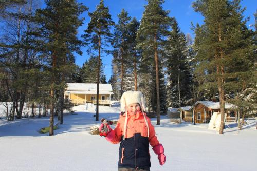 a little girl standing in the snow at Keitaanniemen lomamökki in Haapamäki