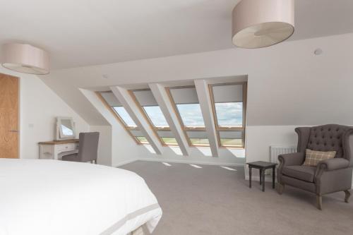 een slaapkamer met een bed, een stoel en ramen bij Links View - Donnini Deluxe in Prestwick