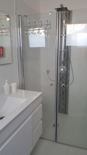a white bathroom with a shower and a sink at Regina's place in Or ‘Aqīvāh
