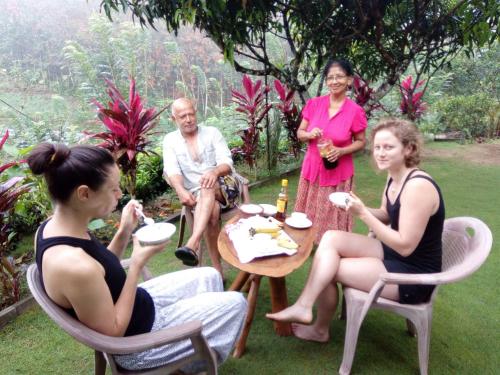 un grupo de personas sentadas alrededor de una mesa en Sinharaja Holiday Bungalow, en Tinniyawala