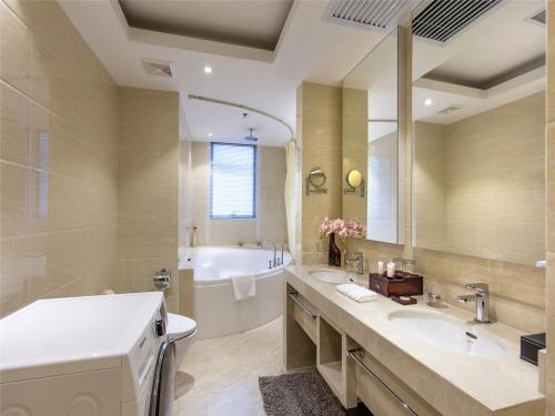 y baño con 2 lavabos, bañera y bañera. en Ariva Tianjin Zhongbei Hotel & Serviced Apartment, en Tianjin