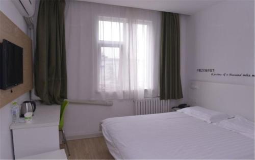 a bedroom with a white bed and a window at Motel Ji'nan Shandong University Shanda Road in Jinan