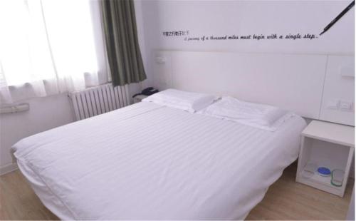 a white bed in a bedroom with a sign on the wall at Motel Ji'nan Shandong University Shanda Road in Jinan
