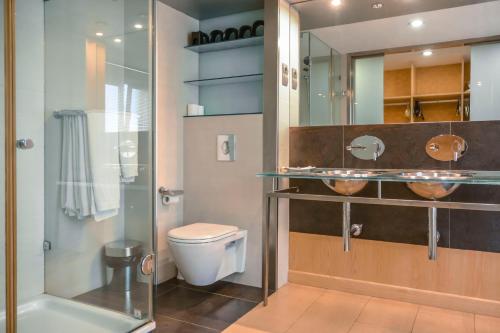 トレモリノスにあるCarihuela Beach Apartamentosのバスルーム(トイレ、ガラス張りのシャワー付)