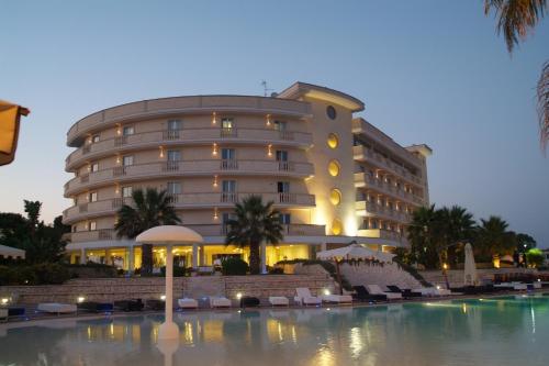 un hotel con piscina di fronte a un edificio di Grand Hotel Dei Cavalieri a Maruggio