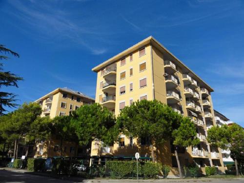 ビビオーネにあるGiuliana - Appartamentiの目の前に木が立ち並ぶ高い黄色の建物