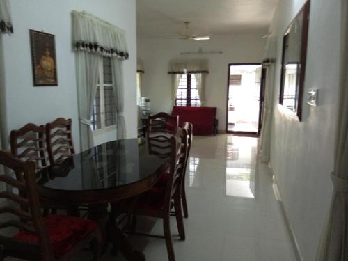 a dining room with a glass table and chairs at Coconut Grove in Cochin