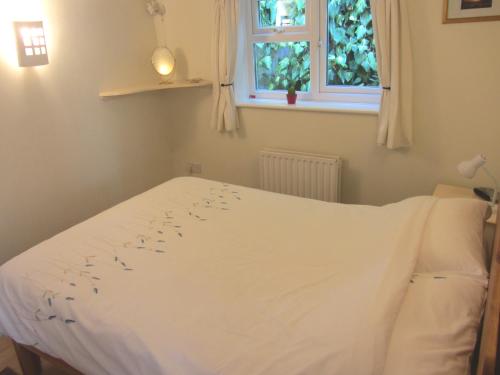 a white bed in a bedroom with a window at The Stable in Eastleigh