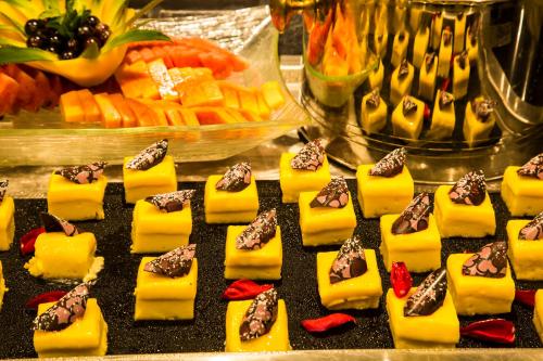 a bunch of desserts on a table with vegetables at Regency Tirunelveli By GRT Hotels in Tirunelveli