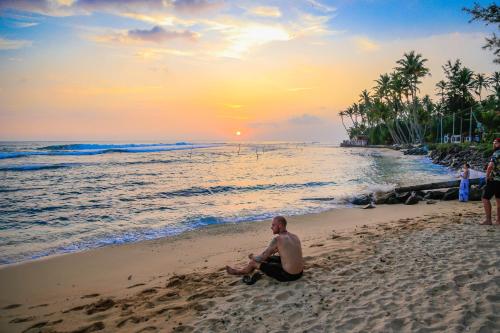 a man sitting on the beach watching the sunset at Amazing Villa in Matara