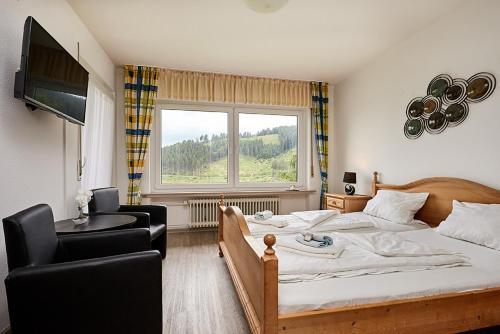 a bedroom with a bed and a chair and a window at Pension Haus am Einberg in Meschede