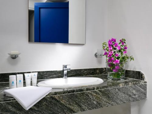 a bathroom counter with a sink and a vase of flowers at TH Ostuni - Ostuni Village in Ostuni