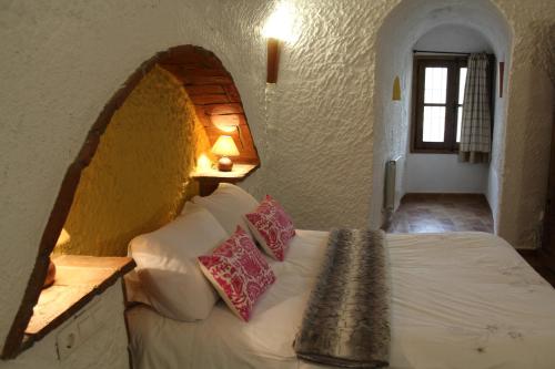 a bedroom with a bed with a brick wall at Cuevas Hammam Abuelo Jose in Purullena