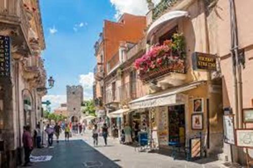 un grupo de personas caminando por una calle con edificios en casa Taormina, en Letojanni