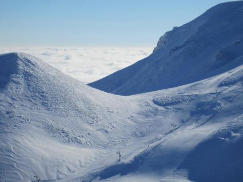 a mountain covered in snow with mountains in the background at L'Esprit du Bois in Aydat