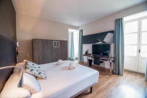 a bedroom with a bed and a desk and a television at Petit Palace Santa Cruz in Seville