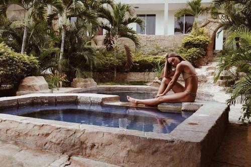 a woman sitting in front of a swimming pool at ME Hotel & Villas - Montañita Estates in Montañita